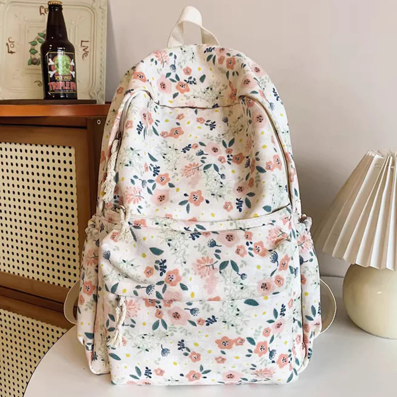 A floral print backpack set featuring a light background with pink and green flowers, displayed on a white surface.
