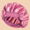 A solid satin wide brim shower cap in a dusty rose color shown from above.