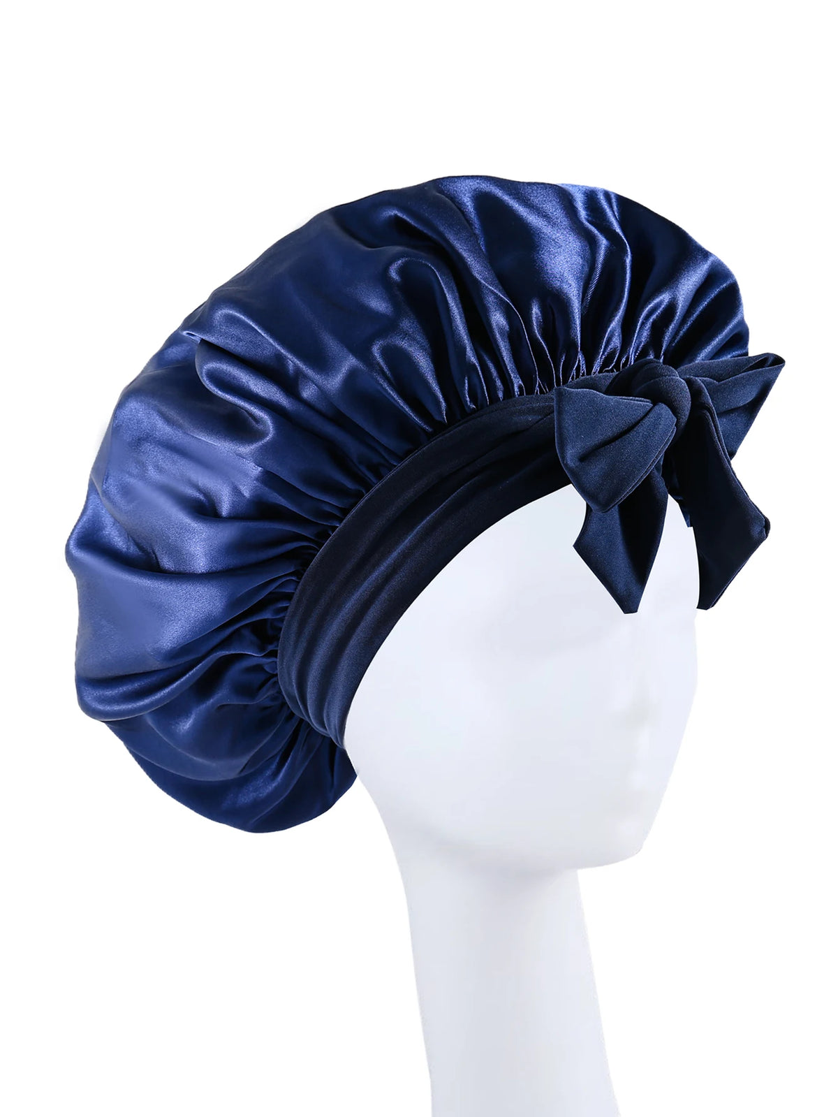 A navy blue silky satin sleep bonnet tied with a bow displayed on a white mannequin head.