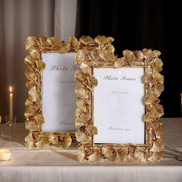 A golden ginkgo leaf photo frame with a white insert displayed on a table.