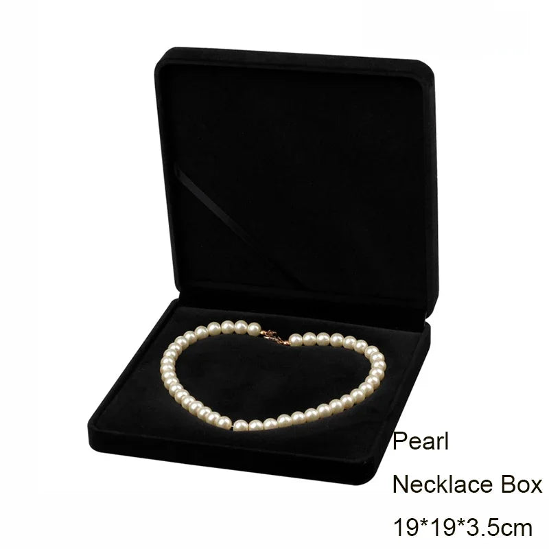 A black velvet necklace box containing a strand of white pearls.