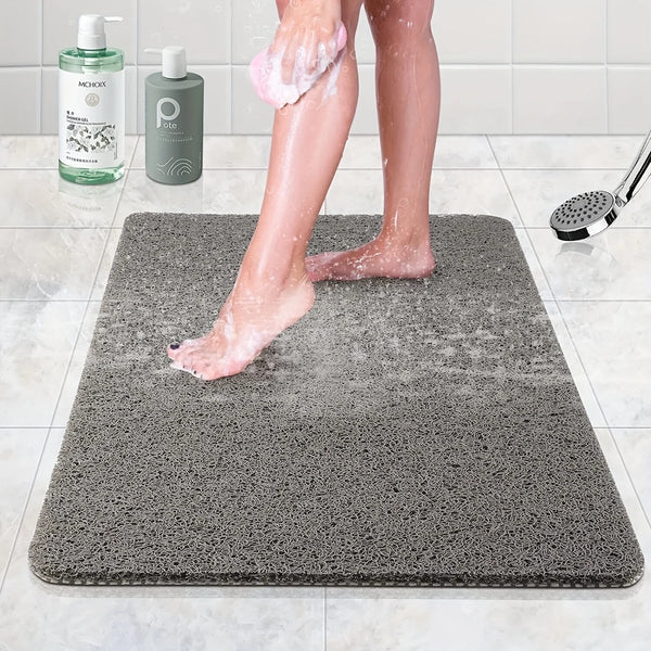 A person's legs are standing on a gray microfiber bathroom mat while using a lotion or soap.
