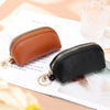 A brown leather key organizer wallet with a gold zipper closure is shown next to a black leather version.
