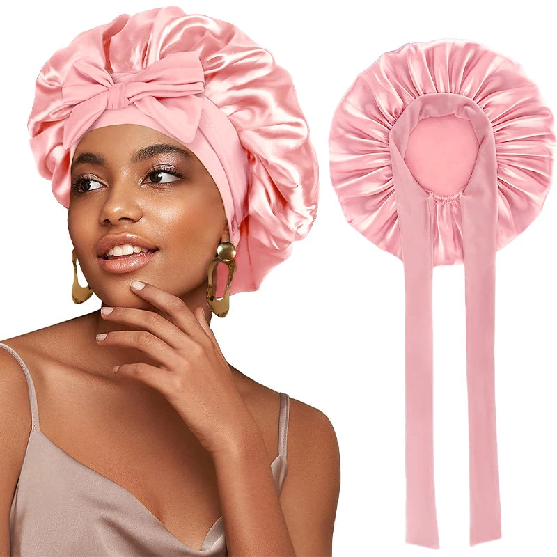 A woman models a pink satin sleeping cap with an adjustable tie band.