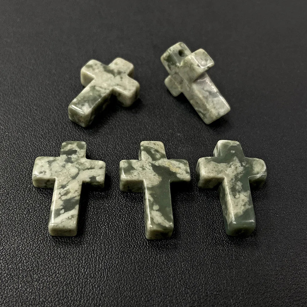 Three natural agate and jasper cross pendant charms are displayed on a dark surface.