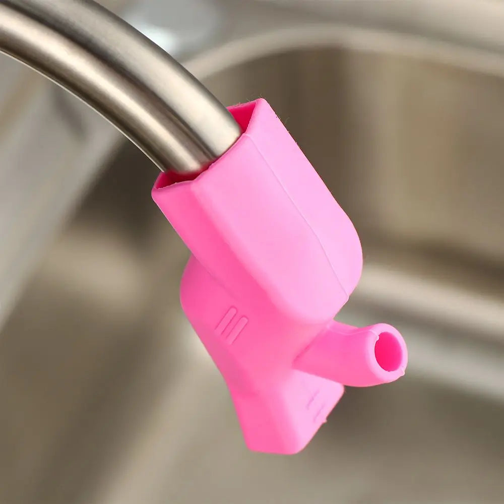 A pink flexible silicone faucet extender attached to a metal faucet, used for easy washing.
