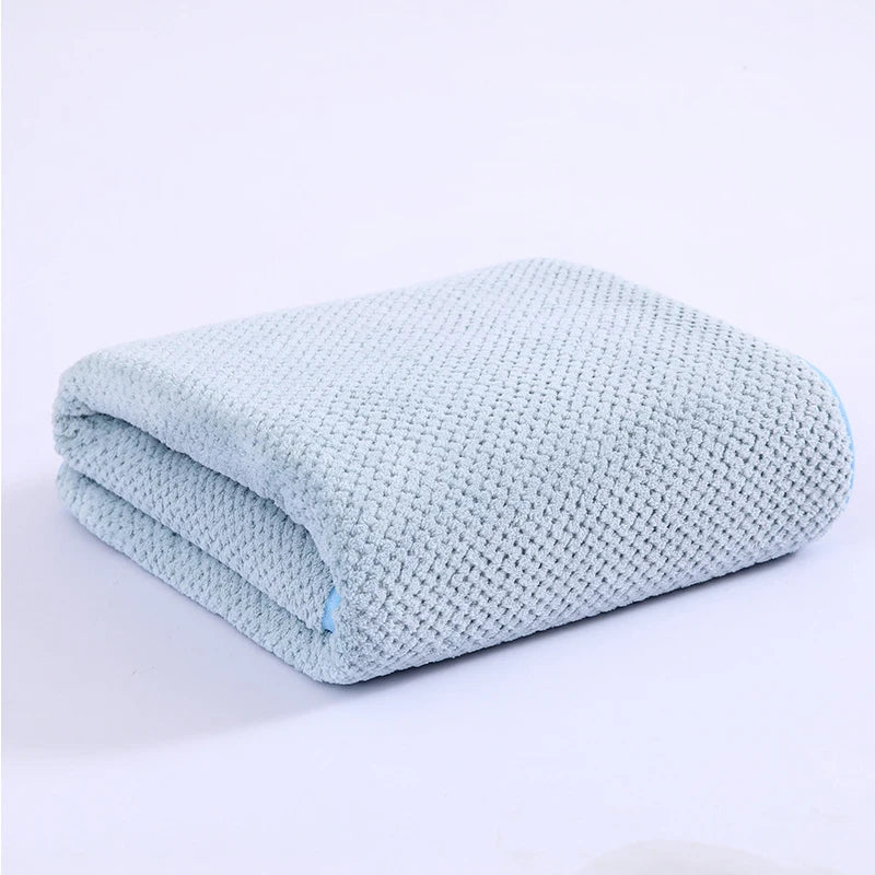Light blue thickened microfiber bath towel folded and displayed on a white surface.