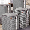 A set of black and white checkered non-woven quilt storage boxes with clear windows on a wooden surface.