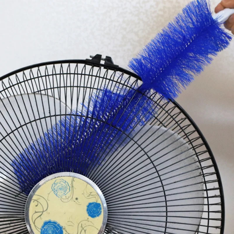 A close-up of a blue bendable fan brush being used for deep cleaning on a fan grille.