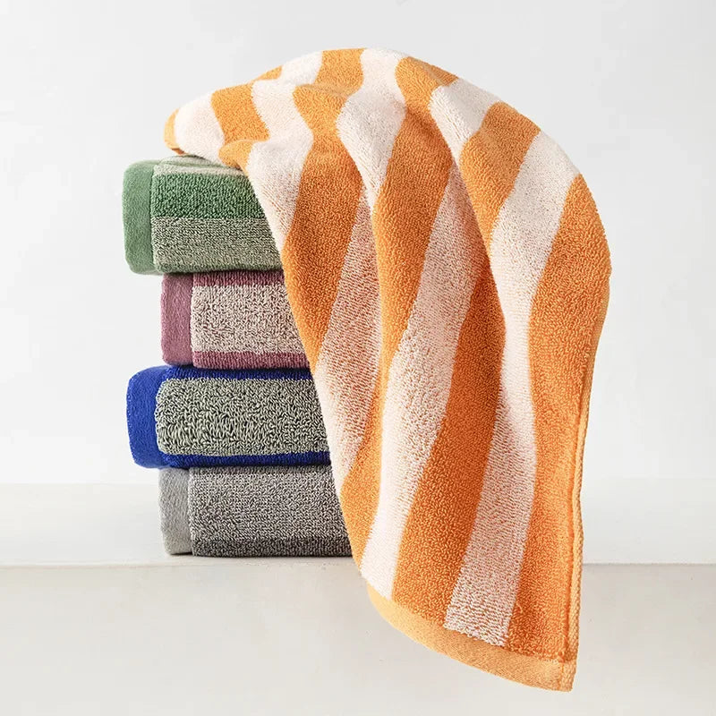 A stack of plaid cotton bath towels in shades of orange, green, purple, and blue.
