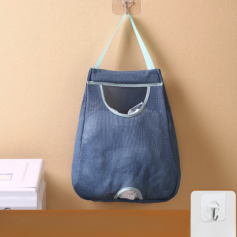 A dark blue mesh garbage bag storage organizer hanging on a wall with light blue straps.
