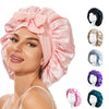 Pink silky satin sleep bonnet with a large bow and various hair accessories shown on a model's head