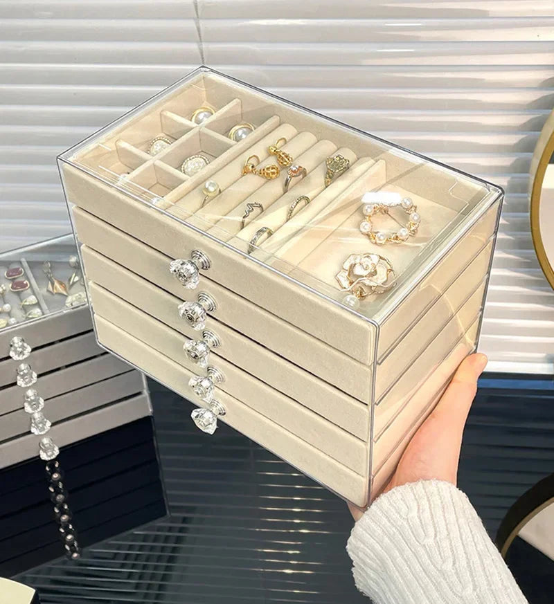 A clear acrylic 5-tier desktop jewelry organizer rack filled with various rings and jewelry, held by a hand.