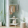 A white multi-layer corner coat rack displaying various beige and cream coats and a plaid scarf against a light green wall.