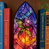 Porta-velas de dragón gótico con diseño de vitral colorido junto a libros.