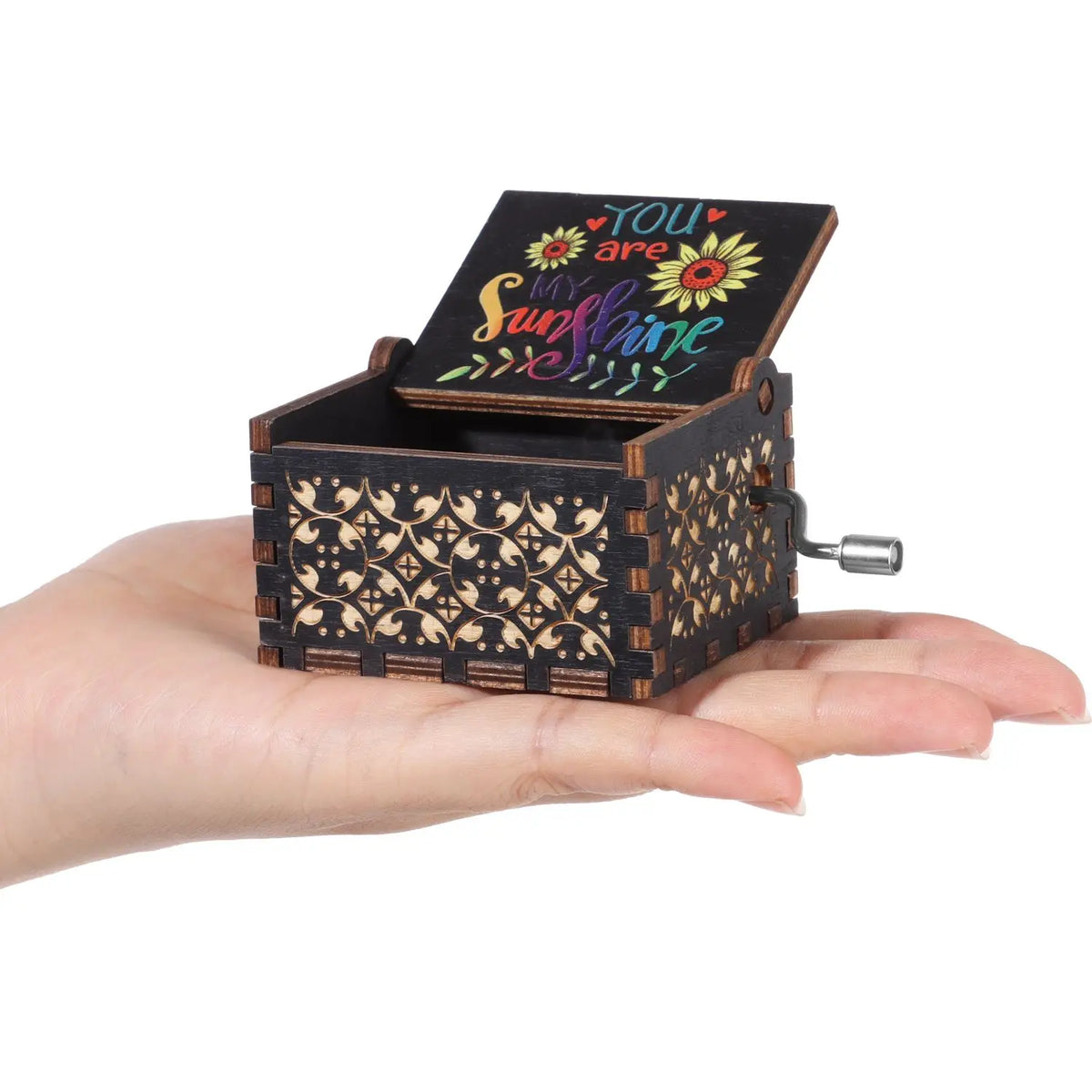 Una caja de música de madera manual con tapa que dice "Eres mi sol" sostenida en una mano.