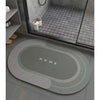 A gray anti-slip floor mat with the word HOME embossed on it, placed in front of a dark glass cabinet.
