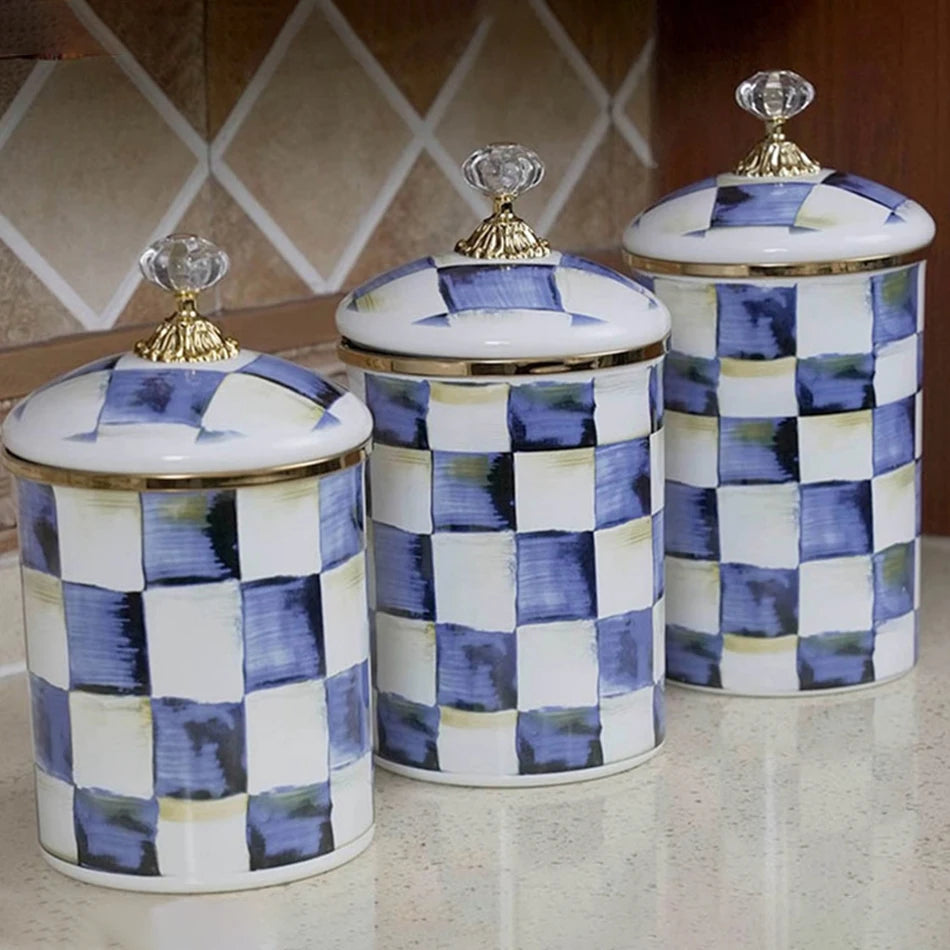 A set of three retro enamel storage jars with white and blue checkered patterns and gold lids.
