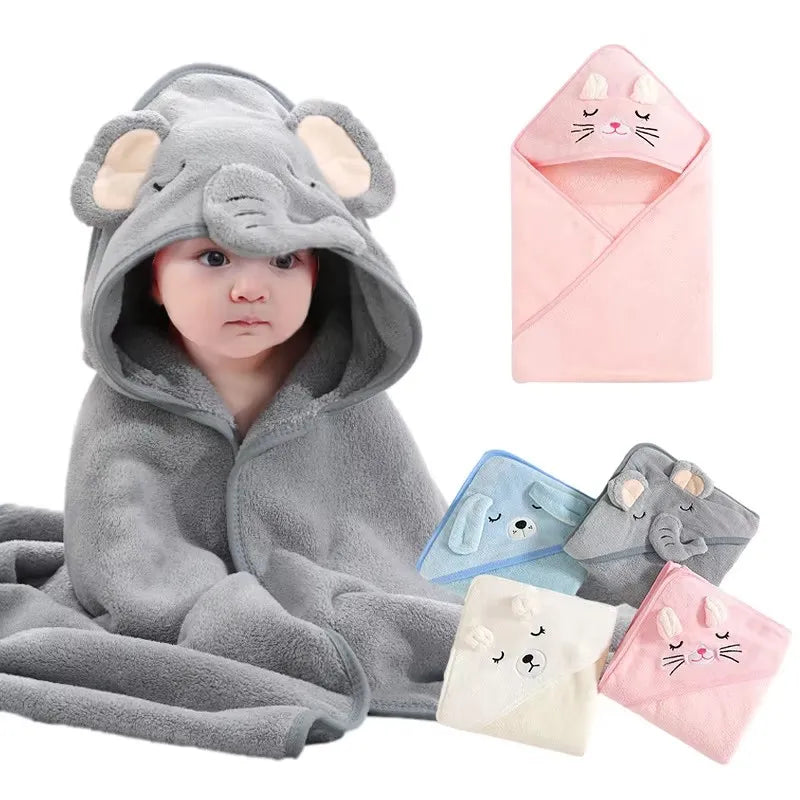 Graue Elefantenplüschpuppe mit Kapuze neben einem rosa Babyhandtuch und Wickelset