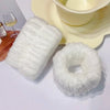 A set of white microfiber wrist sweatbands for face washing and skincare placed next to a yellow bowl.