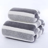 A stack of gray and white striped microfiber bath towels rolled neatly.