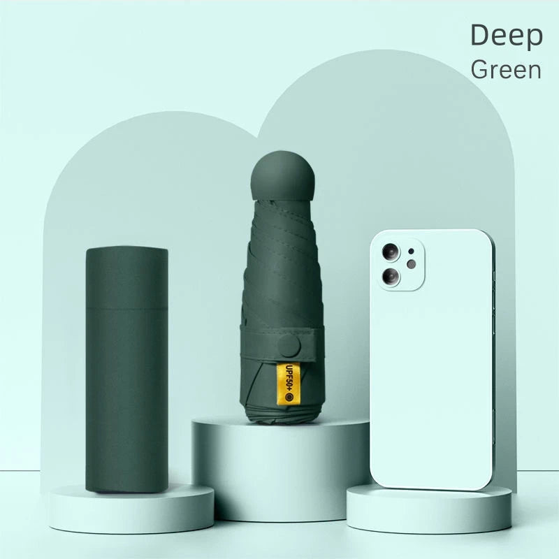A dark green folding UV protection umbrella is displayed next to a white smartphone against a light green background.