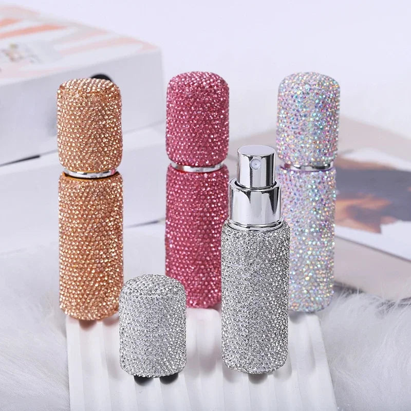 A collection of glittery diamond glass perfume spray bottles in various shades of pink and silver.