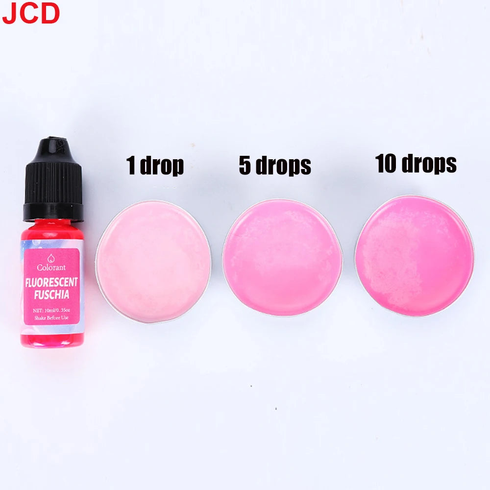A bottle of fluorescent fuschia liquid candle dye with dropper tips next to three pink cosmetic discs showing 1, 5, and 10 dr