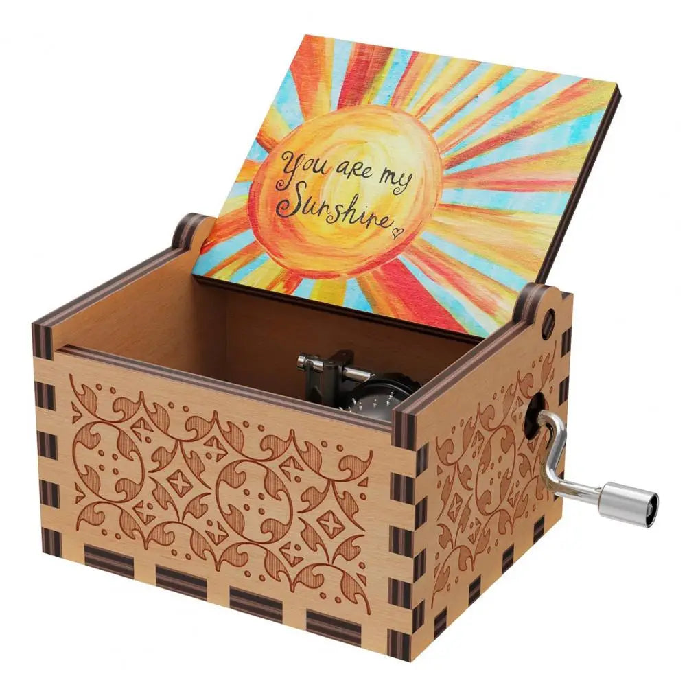 A mini wooden music box with a hand crank, featuring a lid design of sun rays and the text You are my Sunshine.