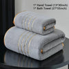 A stack of gray hand towels and a bath towel are displayed on a dark surface.