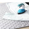A light blue and white folding ironing mat is shown on a white fabric, with a handheld iron resting on it.