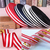 A collection of red, white, and black grosgrain ribbons displayed on a wooden box.