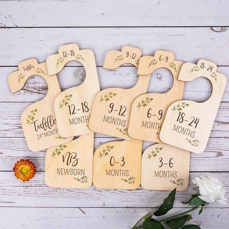 A set of wooden baby closet dividers with age labels ranging from newborn to 24 months.