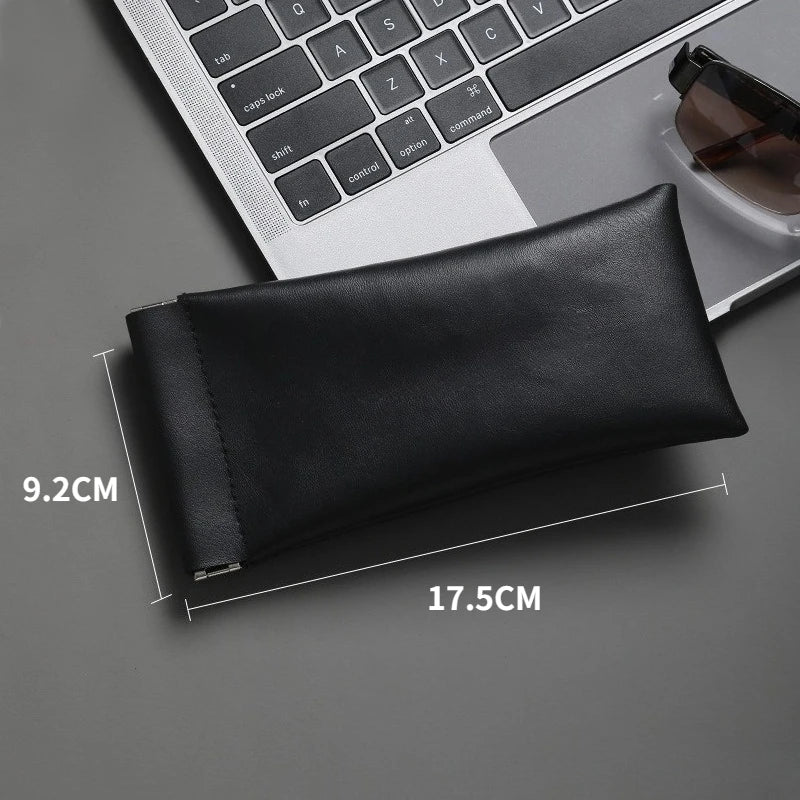 Black PU leather squeeze eyeglasses case shown next to a laptop keyboard and sunglasses.