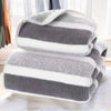 A stack of gray and white striped microfiber bath towels on a white surface.