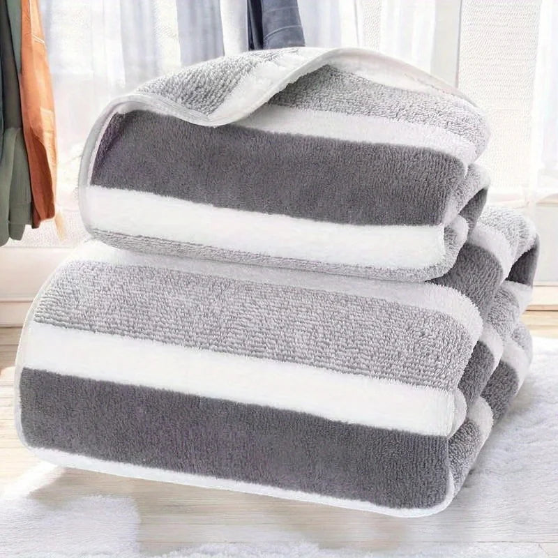 A stack of gray and white striped microfiber bath towels on a white surface.