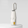 A white compact folding umbrella with a textured handle and UV protection feature standing on a white surface.