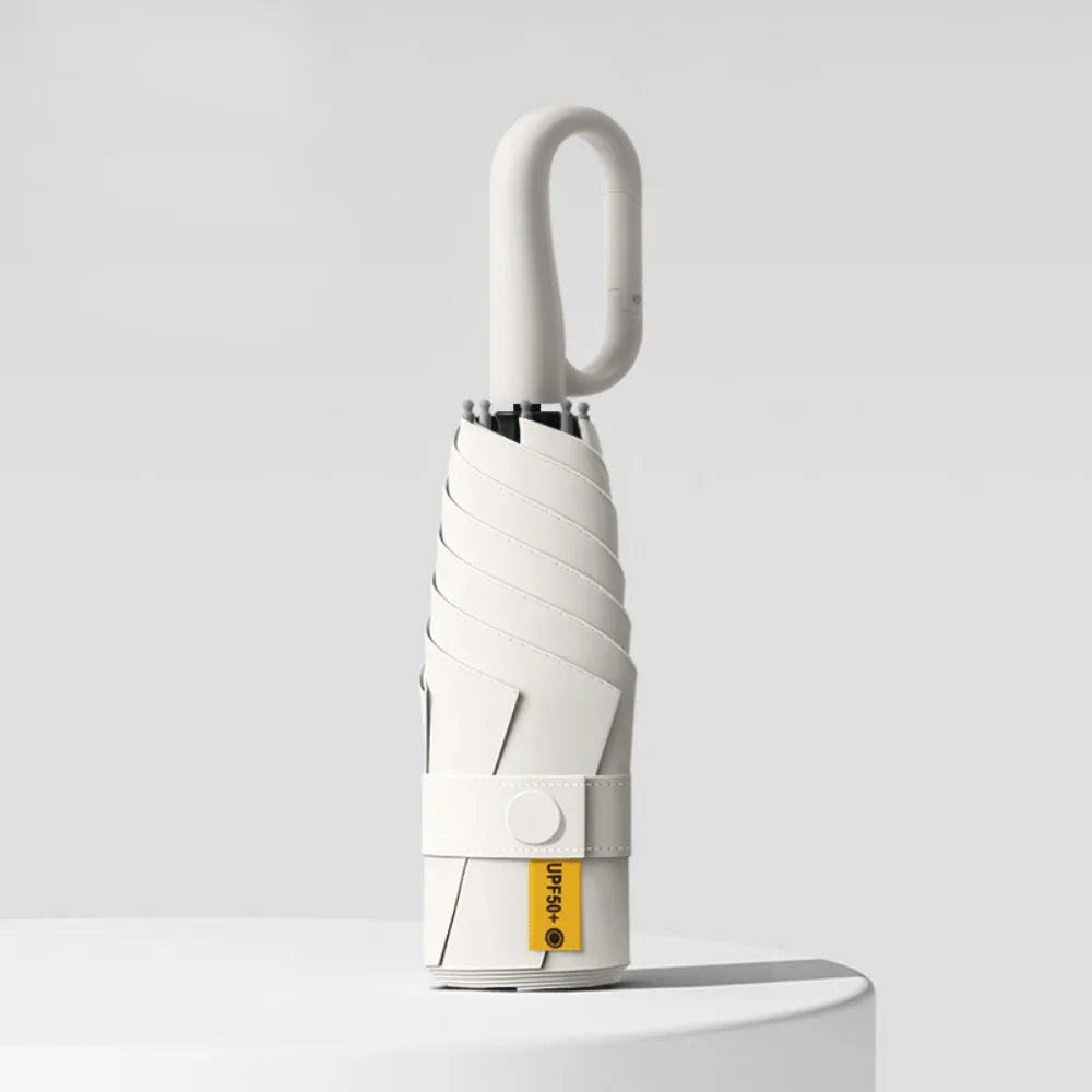 A white compact folding umbrella with a textured handle and UV protection feature standing on a white surface.
