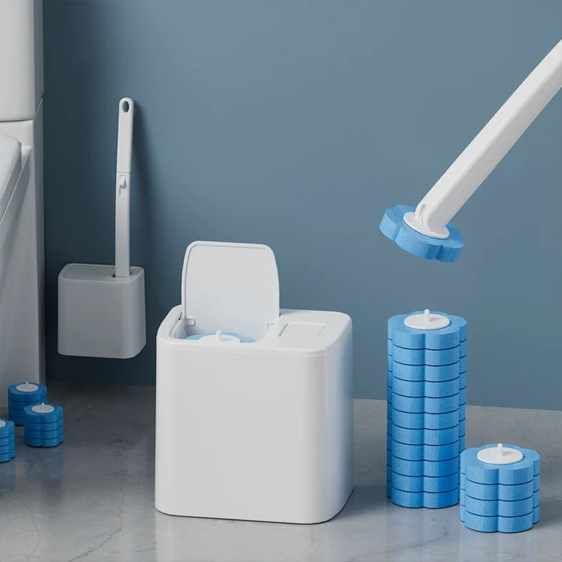 Kit de brosse à toilettes jetable blanche avec manche et disques de nettoyage bleus, sur un mur bleu.