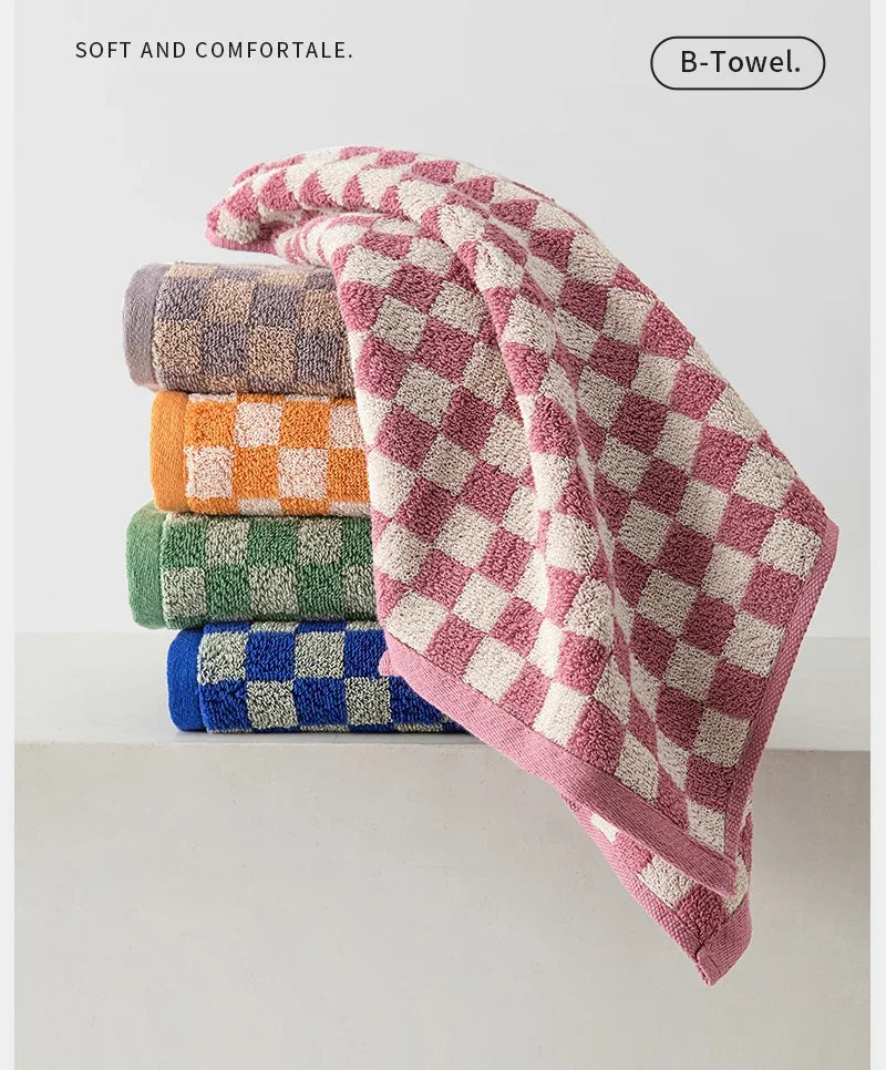 A stack of plaid cotton bath towels in various colors including purple, orange, green, and blue.