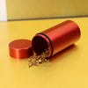 A copper-colored airtight aluminum stash jar lying on a yellow surface with some loose powder spilled out.