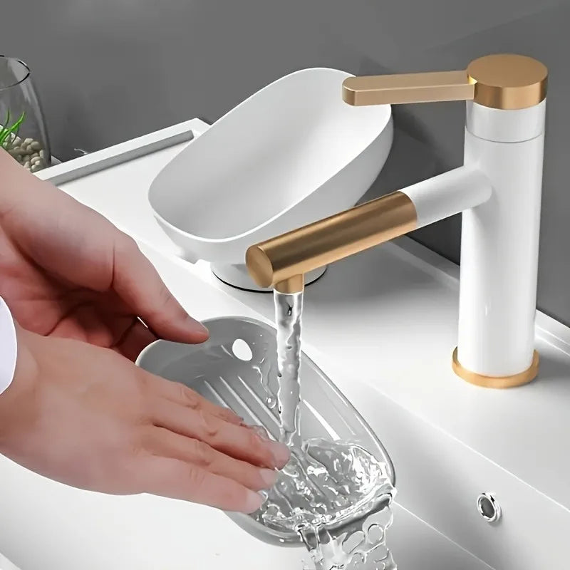 A hand is pouring water into a clear dish from a modern faucet with a gold finish.