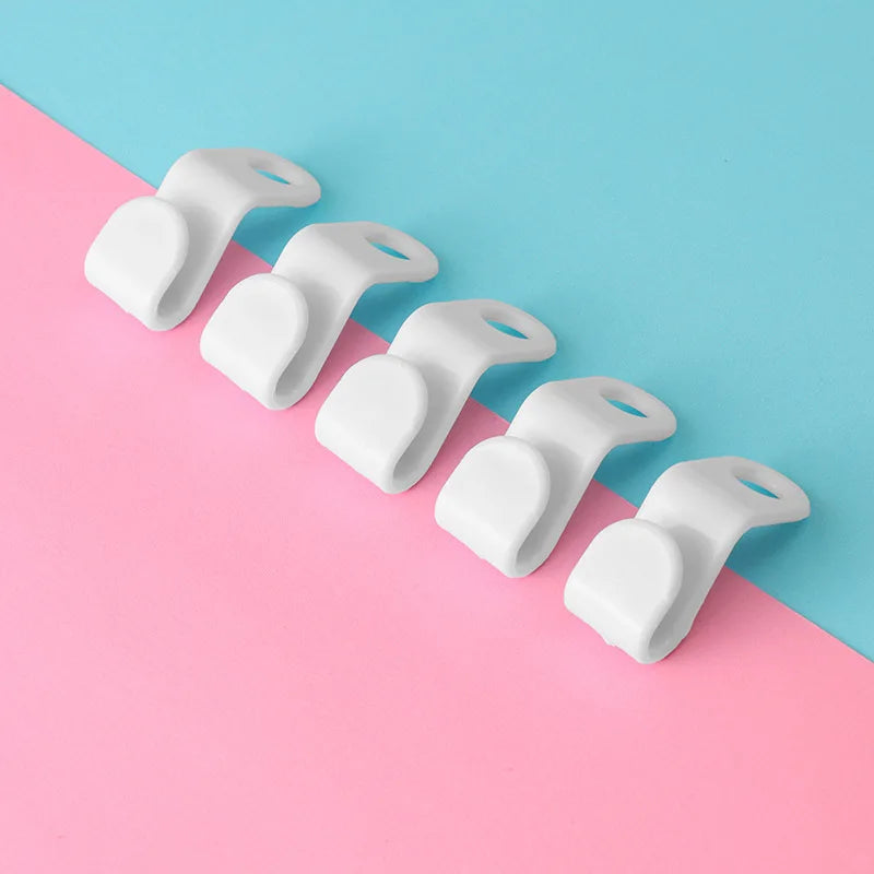 A row of white plastic clothes hanger hooks arranged diagonally on a pink and blue background.
