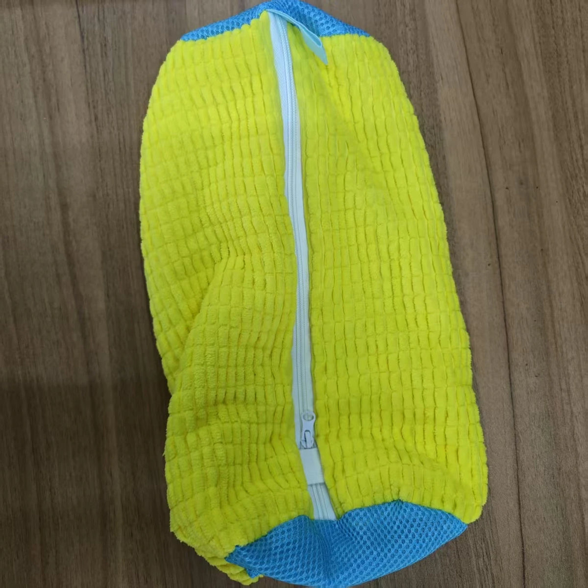 A bright yellow and blue durable shoe washing bag with a white zipper.