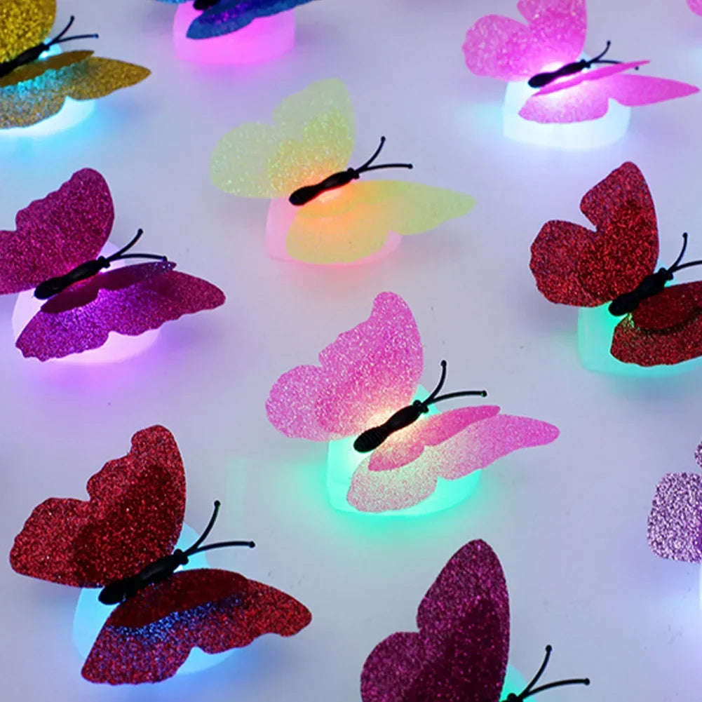 A collection of luminous 3D butterfly wall lights in various shades of pink, purple, and orange illuminating a white surface.