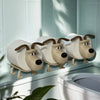 A decorative toilet paper holder shaped like a dog sitting on a white ceramic surface.