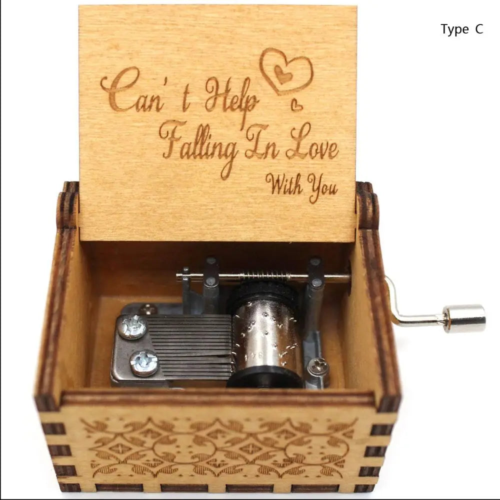 A vintage engraved wooden music box with a lid featuring the text Can't Help Falling In Love With You and a metal cylinder in
