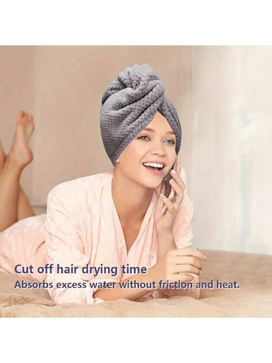 A woman is smiling while using a gray microfiber hair drying towel wrap to dry her hair.