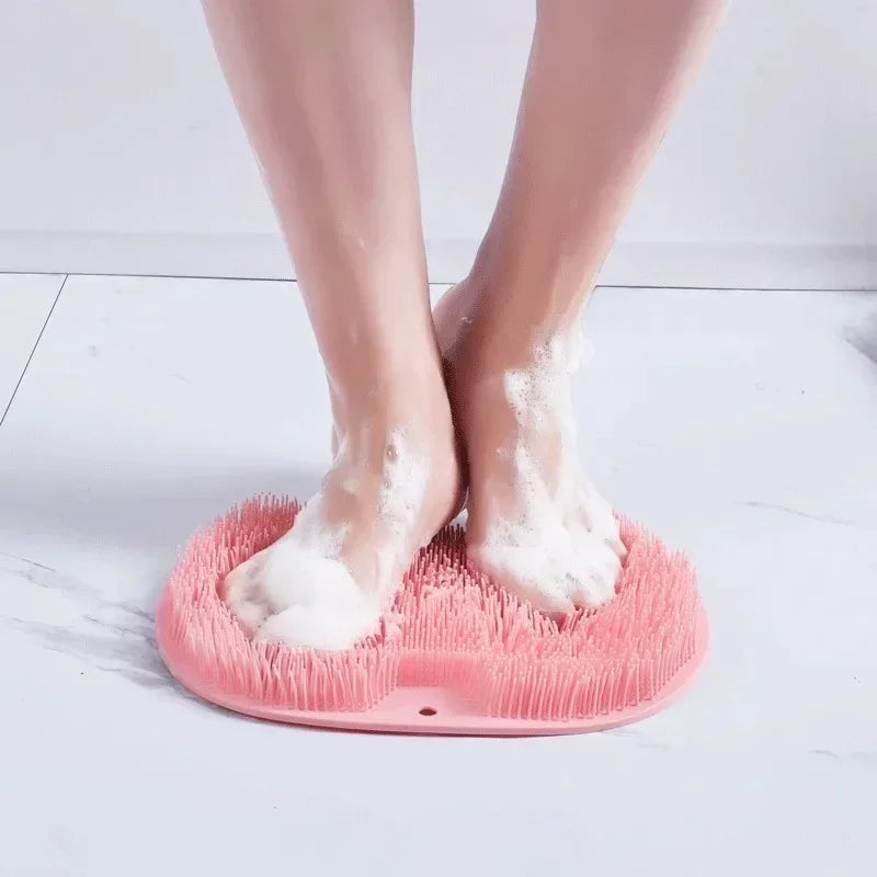 Un par de pies descalzos descansando sobre una estera de ducha de masaje de silicona rosa.