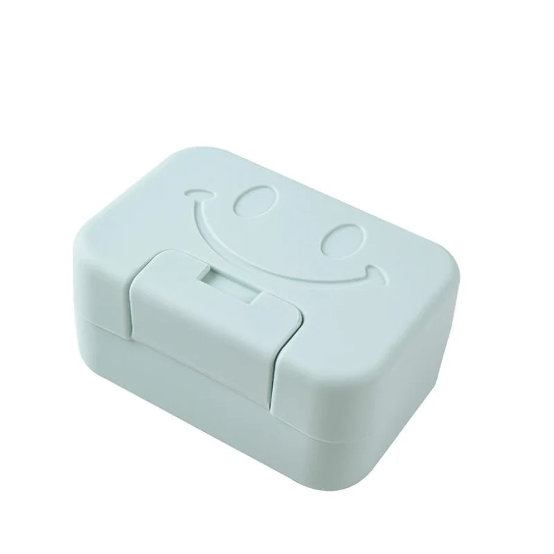A white ceramic soap dish with a lid featuring a smiling face.